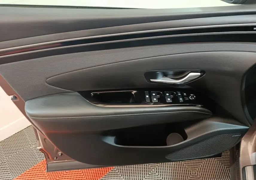 Panneau de porte côté conducteur du Hyundai Tucson marron 2022 avec commandes électriques et finition noire élégante.