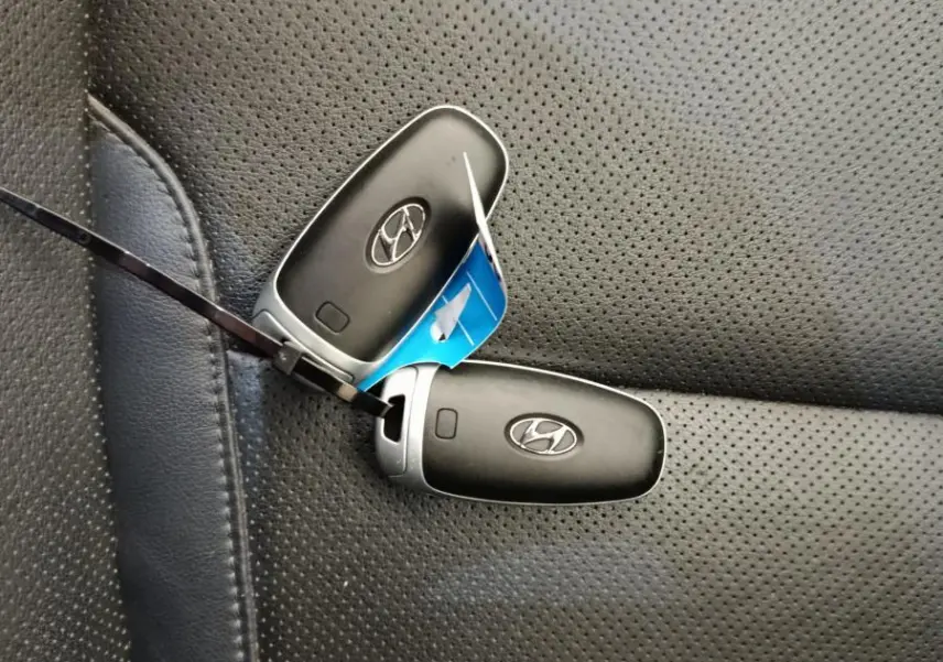Gros plan sur deux clés Hyundai posées sur un siège en cuir noir perforé, intérieur du Tucson hybride rechargeable.