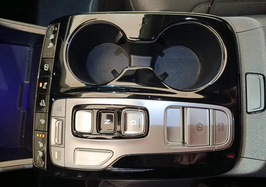 Vue plongeante sur la console centrale noire et argentée du Hyundai Tucson marron, avec commandes de boîte auto et porte-gobelets.