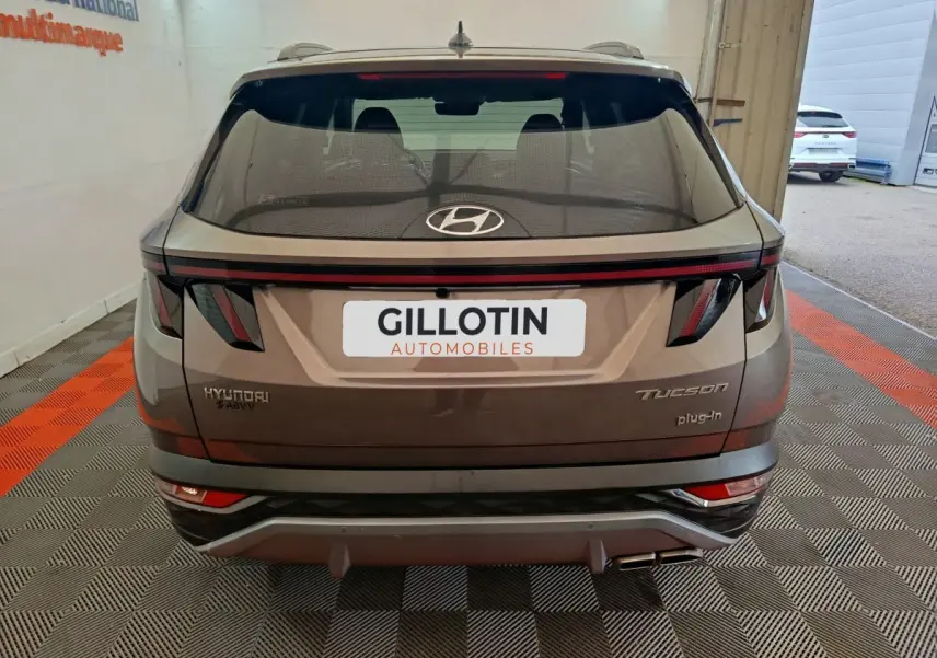 Vue arrière d'un Hyundai Tucson marron plug-in hybride avec feux LED et double sortie d'échappement visible.