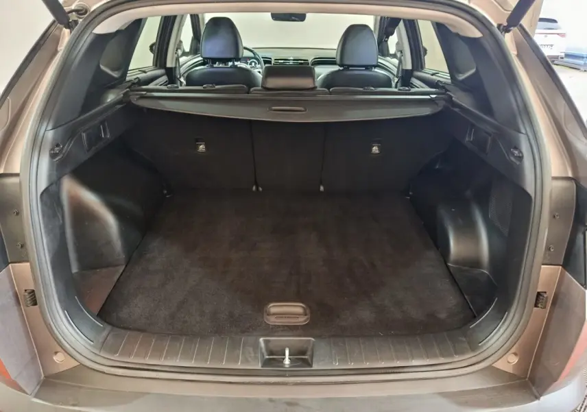 Coffre ouvert vu de l'arrière d'un Hyundai Tucson marron 2022, montrant l'espace de chargement et la plage arrière.