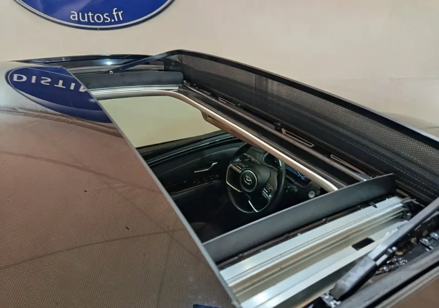 Vue plongeante sur l'intérieur du Hyundai Tucson marron 2022, avec toit ouvrant et volant multifonctions visible.
