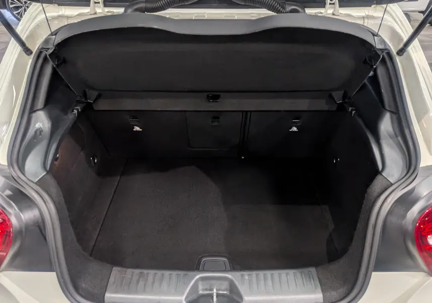 Coffre ouvert vu de dessus d'une Mercedes Classe A 200d blanche de 2016, montrant l'espace de chargement vide et noir.