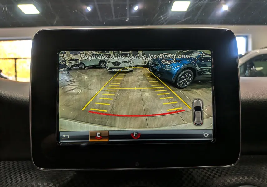 Affichage de la caméra de recul de la Mercedes Classe A 200d blanche, montrant l'arrière avec lignes de guidage jaunes et rouges.