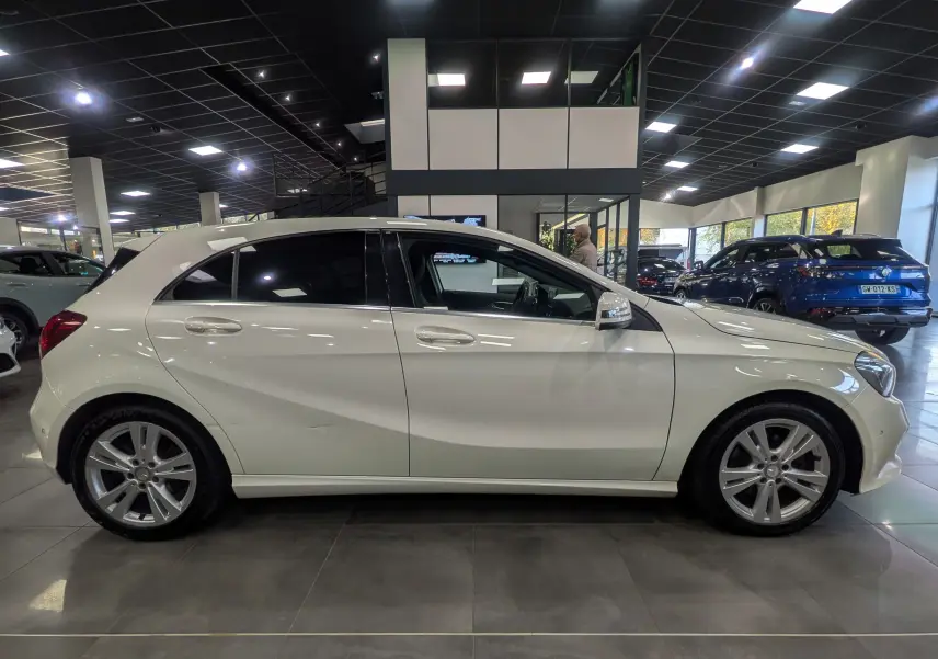 Profil côté gauche d'une Mercedes Classe A 200d blanche en intérieur, soulignant ses lignes épurées et jantes alliage.