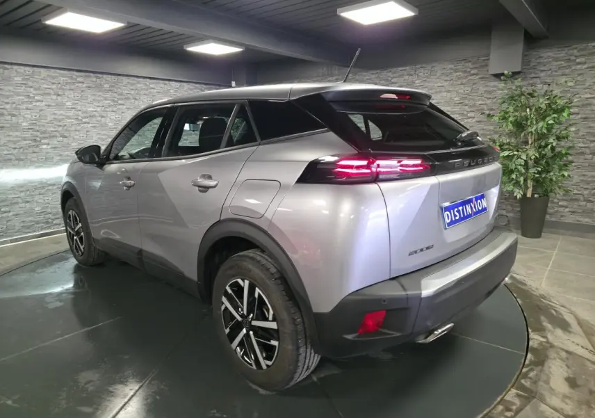 Vue 3/4 arrière droite d'un Peugeot 2008 gris métallisé avec feux arrière LED 3 griffes et jantes noires et argent.