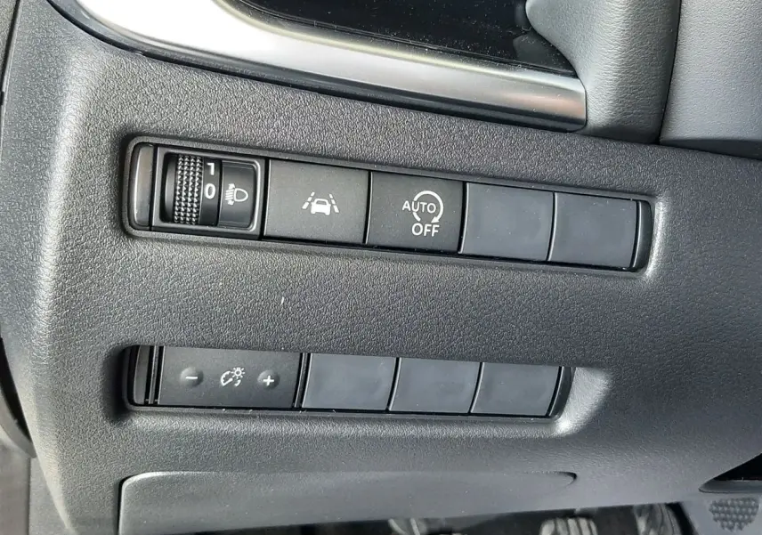 Vue du tableau de bord côté gauche d'un Nissan Qashqai blanc lunaire 2022, avec commandes d'assistance et pédales visibles.