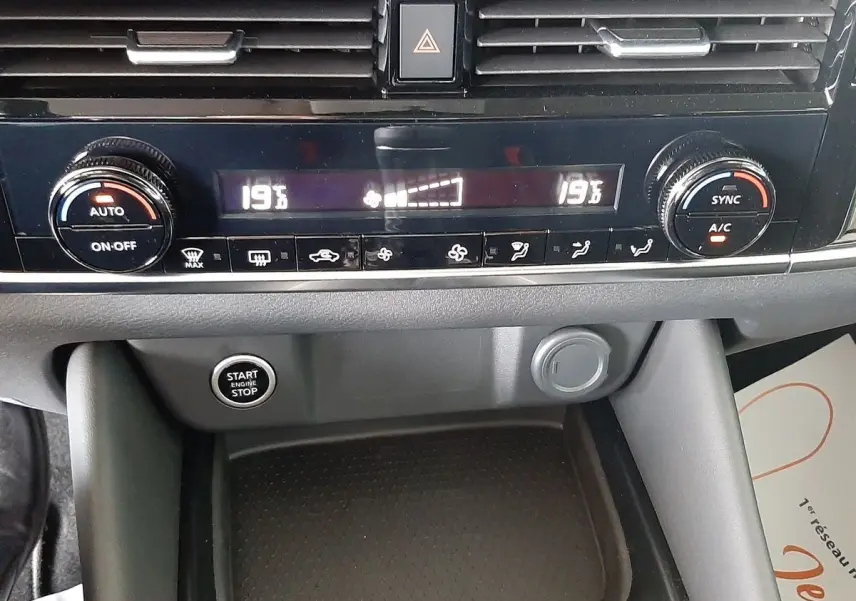 Tableau de bord du Nissan Qashqai blanc lunaire 2022, vue rapprochée sur commandes climatisation et bouton start/stop.