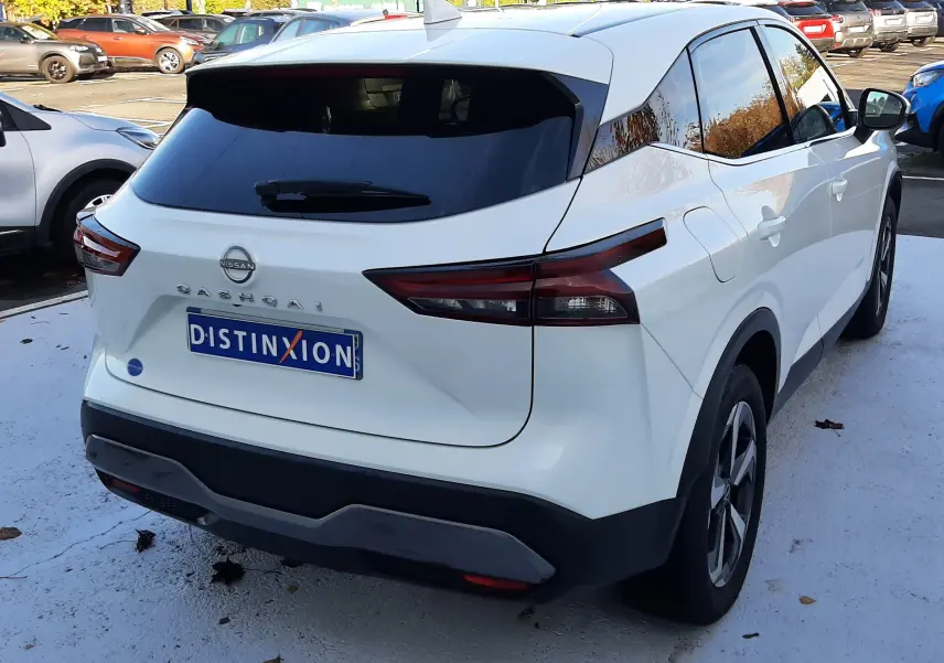 Vue 3/4 arrière droite d'un Nissan Qashqai blanc lunaire 2022 avec vitres teintées et feux arrière LED distinctifs.