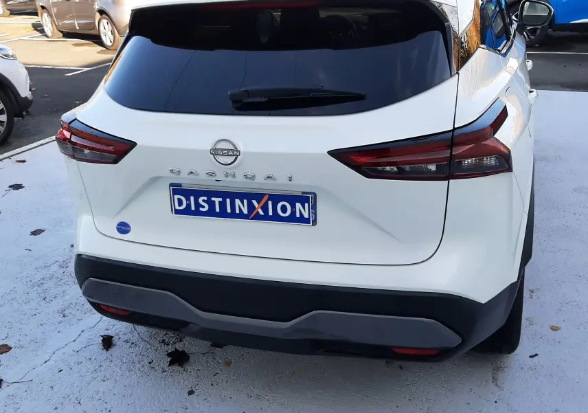 Vue arrière d'un Nissan Qashqai blanc lunaire 2022 avec vitres teintées et plaque Distinxion visible.