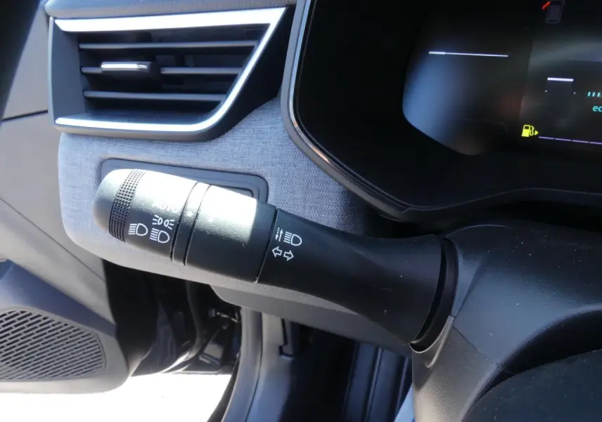 Gros plan sur la commande des feux et clignotants côté gauche du tableau de bord gris clair de la Renault Clio noire.