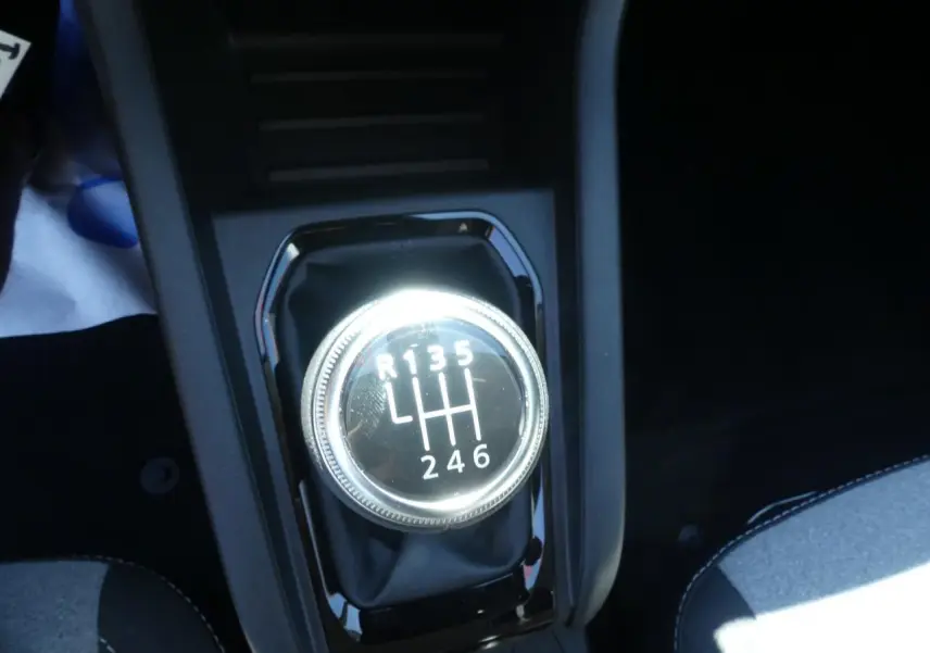 Gros plan sur le levier de vitesses manuel chromé de la Renault Clio noire, entouré de console noire brillante.