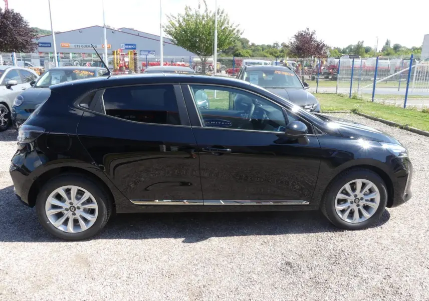 Profil côté gauche d'une Renault Clio noire métallisée 2025 garée sur un sol gravillonné en extérieur.