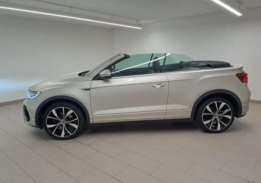Volkswagen T-Roc Cabriolet gris ivoire vue de profil côté gauche, capote noire et jantes alliage 19 pouces visibles.