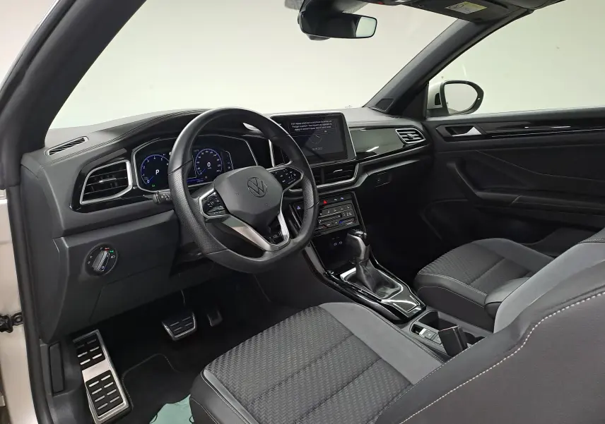 Vue intérieure côté conducteur du Volkswagen T-Roc Cabriolet 2022, tableau de bord noir et volant multifonction.