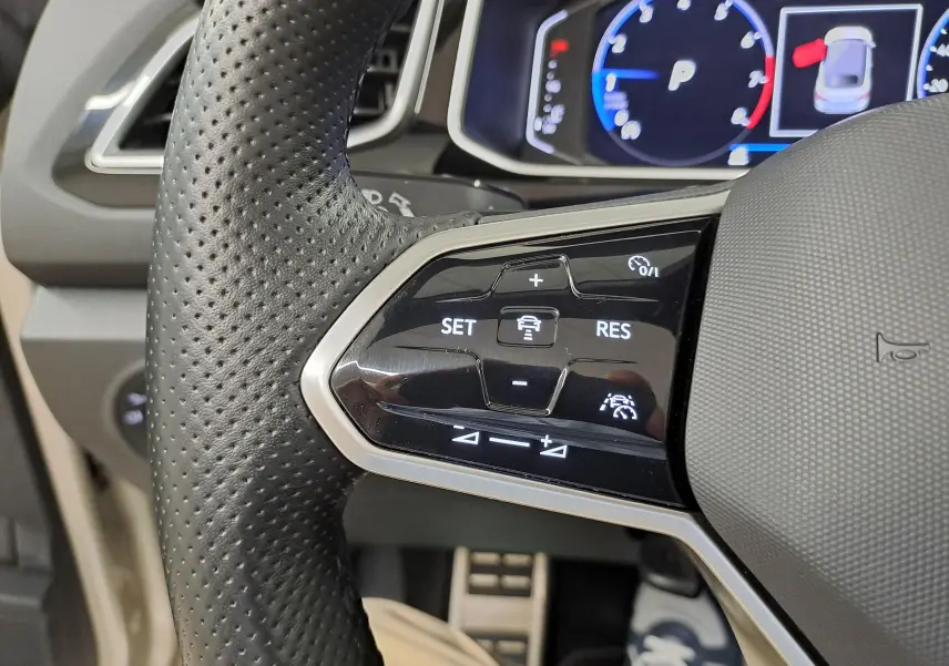 Gros plan sur les commandes de régulateur de vitesse au volant perforé du Volkswagen T-Roc Cabriolet 2022.