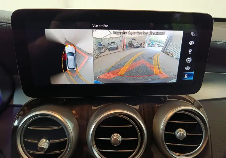 Écran tactile intérieur du Mercedes GLC 300 e Business Line affichant la caméra de recul et l'aide au stationnement.