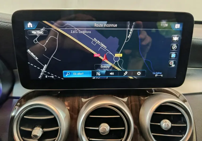 Écran tactile central affichant la navigation, entouré de trois aérateurs ronds sur tableau de bord bois d’un Mercedes GLC noir.