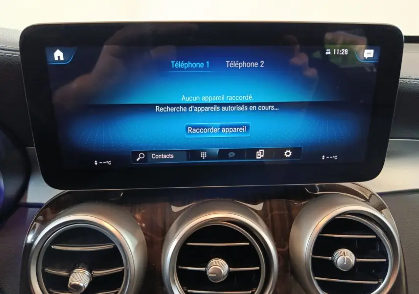 Écran tactile central affichant la connexion Bluetooth, entouré de trois aérateurs ronds sur tableau de bord bois du Mercedes GLC 300 e noir.
