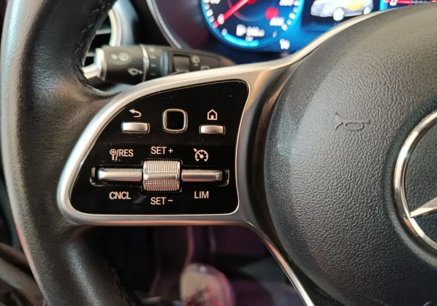 Gros plan sur les commandes du volant cuir noir du Mercedes GLC 300 e Business Line 4Matic, avec tableau de bord numérique en arrière-plan.