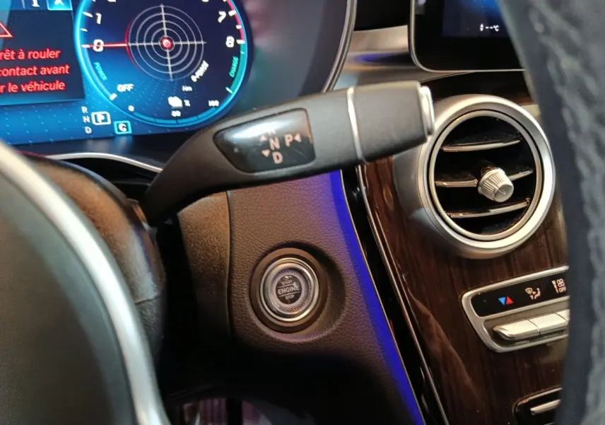 Gros plan intérieur sur le tableau de bord noir du Mercedes GLC 300 e, montrant le bouton démarrage et la commande de boîte automatique.