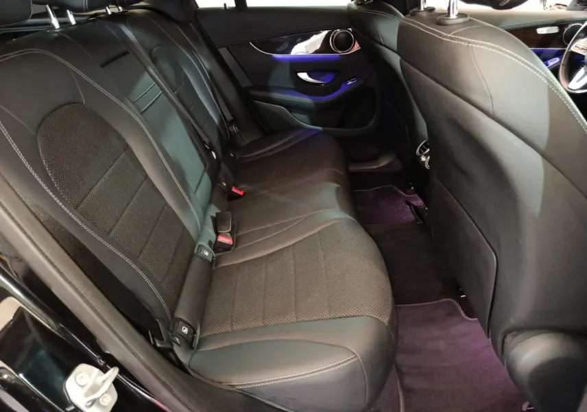 Vue intérieure arrière gauche du Mercedes GLC 300 e Business Line 2020 avec sièges noirs en cuir et éclairage d'ambiance violet