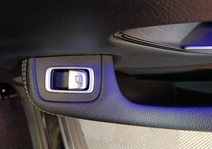 Gros plan sur le bouton de commande de vitre électrique intégré dans la porte intérieure noire du Mercedes GLC 300 e.