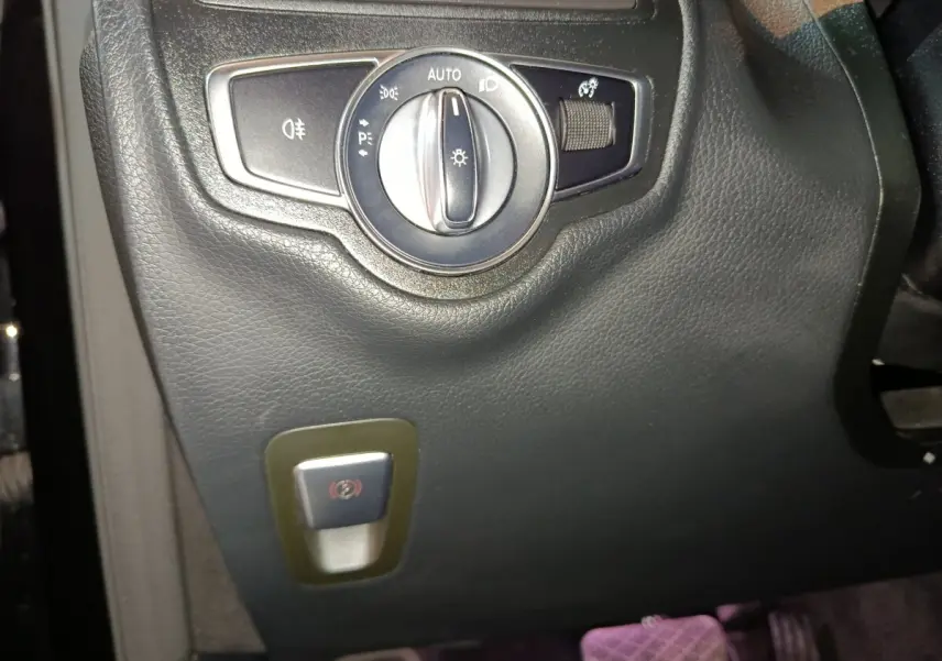 Gros plan sur le bouton des phares et frein à main électrique dans l'habitacle noir du Mercedes GLC 300 e Business Line 2020.