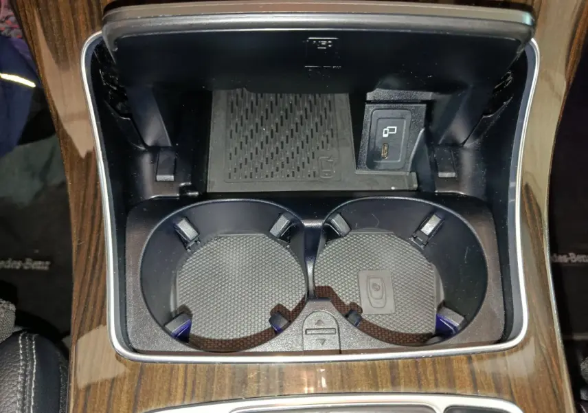 Gros plan sur les porte-gobelets et prise USB dans la console centrale en bois du Mercedes GLC 300 e noir.