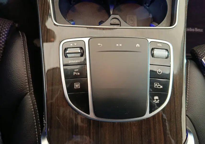 Gros plan sur la console centrale en bois sombre du Mercedes GLC 300 e Business Line avec pavé tactile et commandes multifonctions.