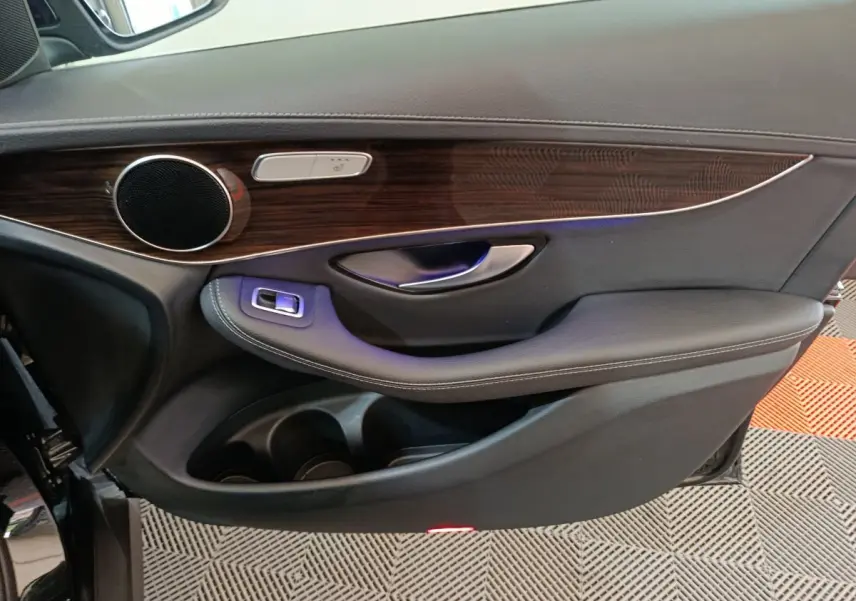 Vue intérieure côté gauche de la porte avant noire du Mercedes GLC 300 e Business Line avec garniture bois et commandes intégrées.