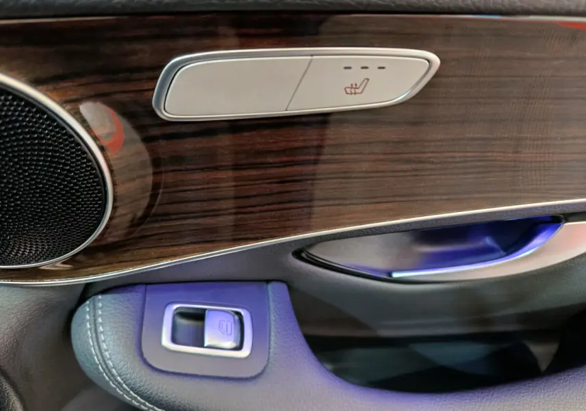 Gros plan sur la portière côté gauche d'un Mercedes GLC 300 e noir, avec commandes de siège chauffant et insert bois.