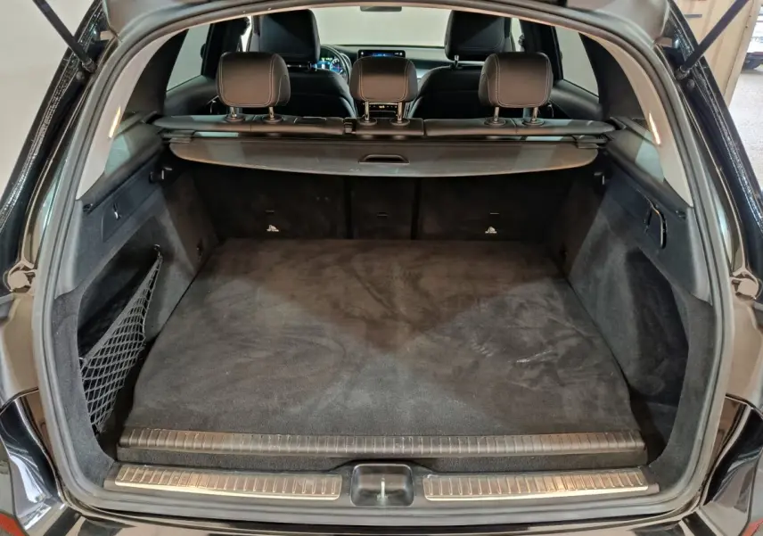 Coffre ouvert vu de l'arrière d'un Mercedes GLC 300 e Business Line noir, avec cache-bagages et sièges arrière visibles.