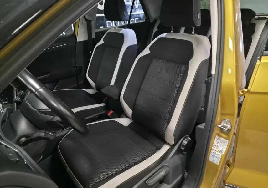 Intérieur avant du Volkswagen T-Roc 2021 avec sièges tissu noir et gris, vue côté conducteur avec porte jaune Curcuma ouverte.