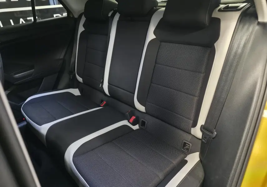 Vue latérale intérieure montrant la banquette arrière en tissu noir avec surpiqûres blanches du Volkswagen T-Roc orange 2021.
