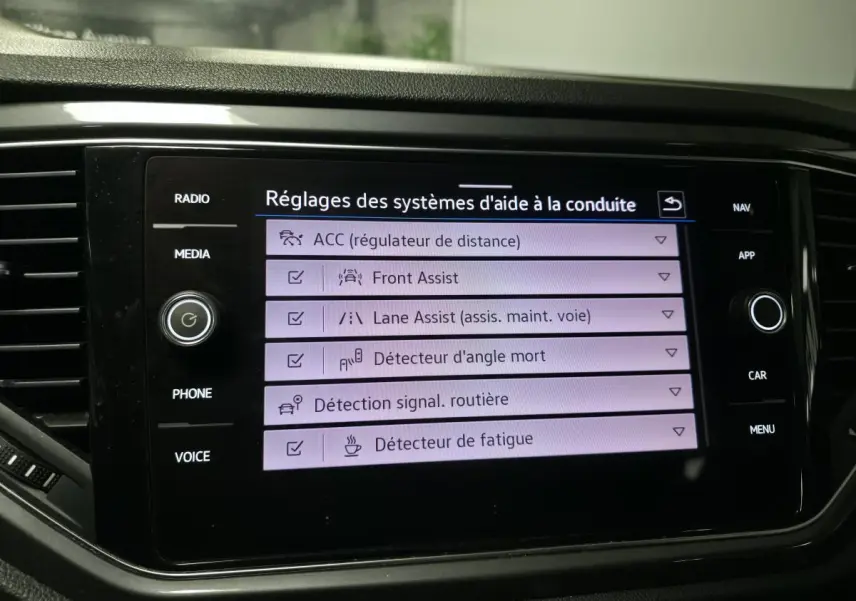 Écran tactile central du Volkswagen T-Roc affichant les réglages des aides à la conduite avec interface noire brillante