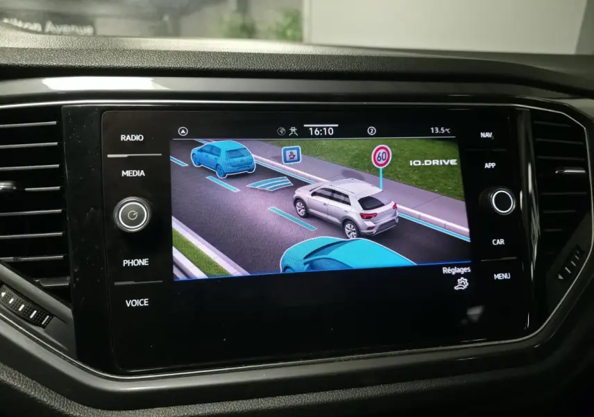 Écran tactile intérieur montrant l'assistance à la conduite avec un SUV gris en vue arrière sur la route virtuelle