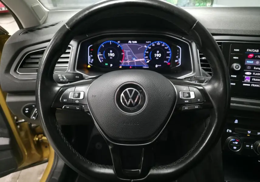 Vue centrée sur le volant en cuir noir du Volkswagen T-Roc 2021 avec tableau de bord numérique et écran tactile.