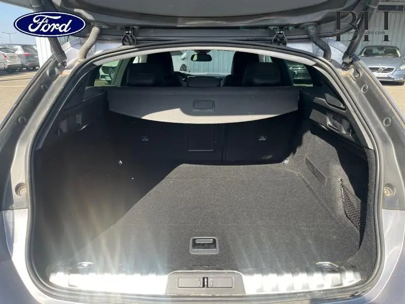 Coffre ouvert vu de l'arrière d'un Peugeot 508 SW gris Artense avec cache-bagages et intérieur noir.