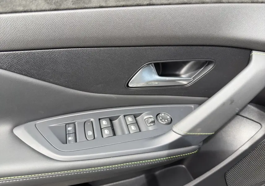 Détail de la porte côté gauche de la Peugeot 308 gris Selenium, avec commandes de vitres et surpiqûres vert Adamite.