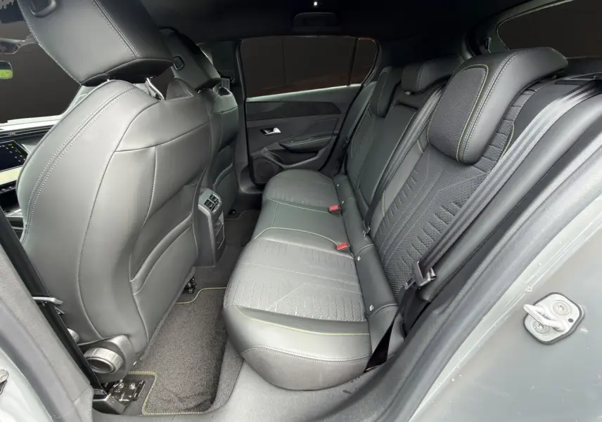 Vue côté droit de l'habitacle arrière gris sélénium de la Peugeot 308 GT 2026 avec sellerie tissu et surpiqûres vertes.