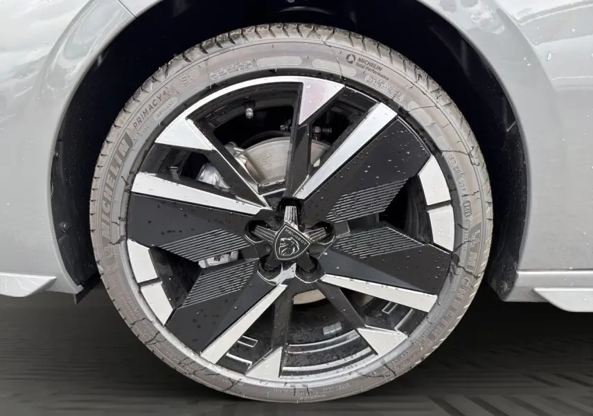 Gros plan sur la jante alliage 18'' bi-ton noir et argent avec logo Peugeot, sur roue avant droite gris selenium.
