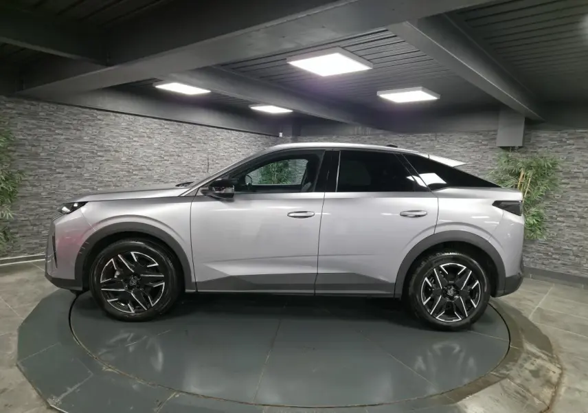 Vue de profil côté gauche du Peugeot 3008 gris métallisé 2025 avec jantes alliage noires et toit noir.