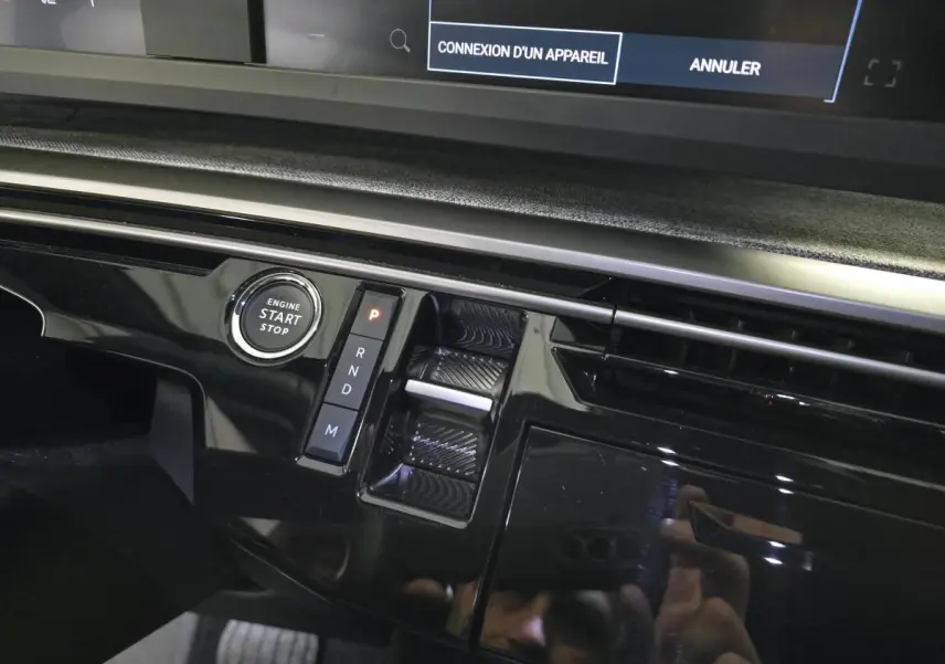 Gros plan sur la console centrale noire laquée du Peugeot 3008 gris, avec bouton start/stop et commandes de boîte auto.
