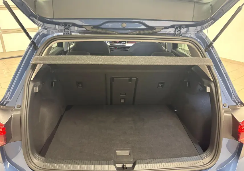Vue arrière du coffre ouvert d'une Volkswagen Golf 1.5 eTSI 116 DSG7 Bleu Anémone, intérieur spacieux et propre.
