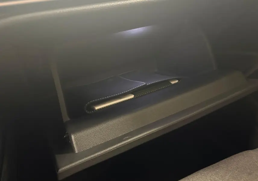 Boîte à gants ouverte de la Volkswagen Golf 1.5 eTSI 116 DSG7 Bleu Anémone, intérieur noir avec surpiqûres.