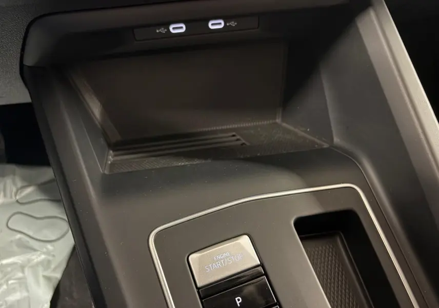 Gros plan sur la console centrale de la Volkswagen Golf 1.5 eTSI 116 DSG7, avec bouton start/stop et rangement noir mat.