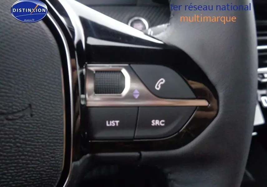 Gros plan sur les commandes du volant d'une Peugeot 2008 rouge Elixir Metal, boutons pour téléphone et liste audio.