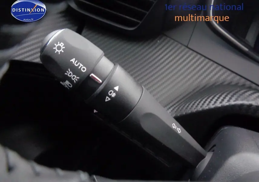 Gros plan sur la commande d'éclairage avec finition carbone dans l'habitacle du Peugeot 2008 rouge Elixir Metal 2023.