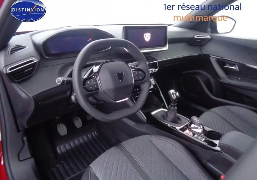 Vue intérieure du poste de conduite du Peugeot 2008 rouge Elixir avec volant multifonction et boîte manuelle.
